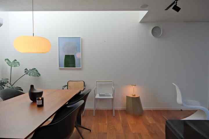 White-walled and wood-toned dining room in Nordic and Wa-Modern style, featuring a large pendant light and green plants in harmony