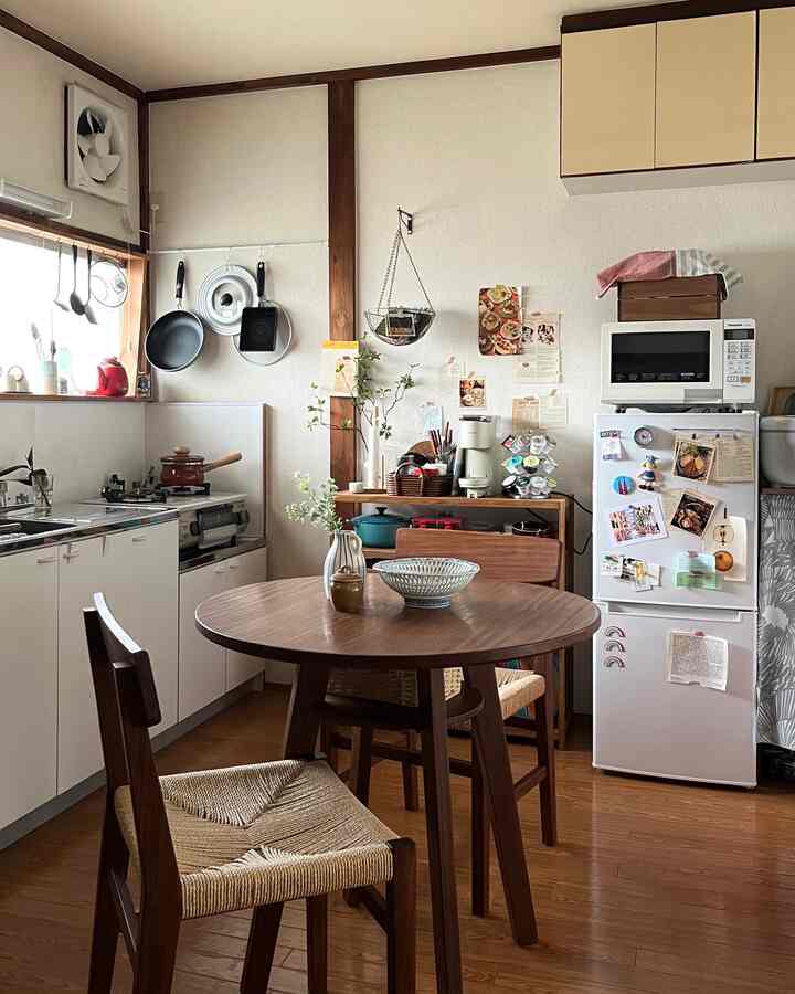 ナチュラルなブラウン色調のキッチン、木製のダイニングテーブルと椅子が配置された印象的な一人暮らしの空間