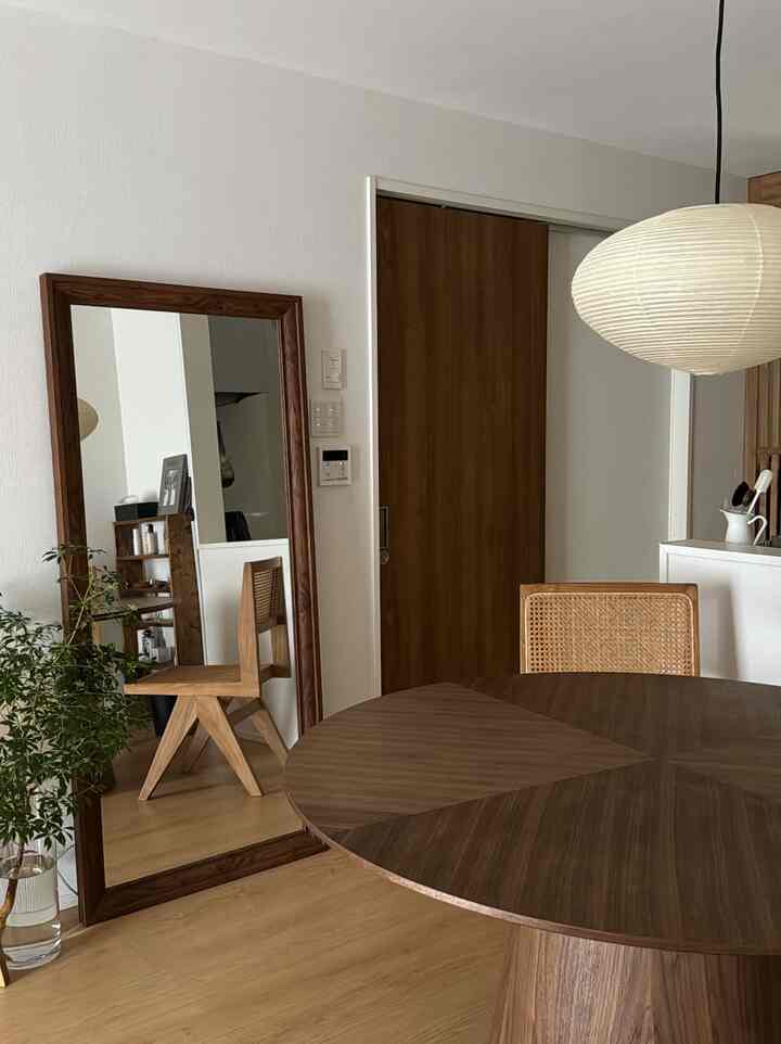 木目調と白を基調としたダイニングスペース、丸いダイニングテーブルと大きな木枠の姿見が配置された落ち着いた和モダンなインテリア