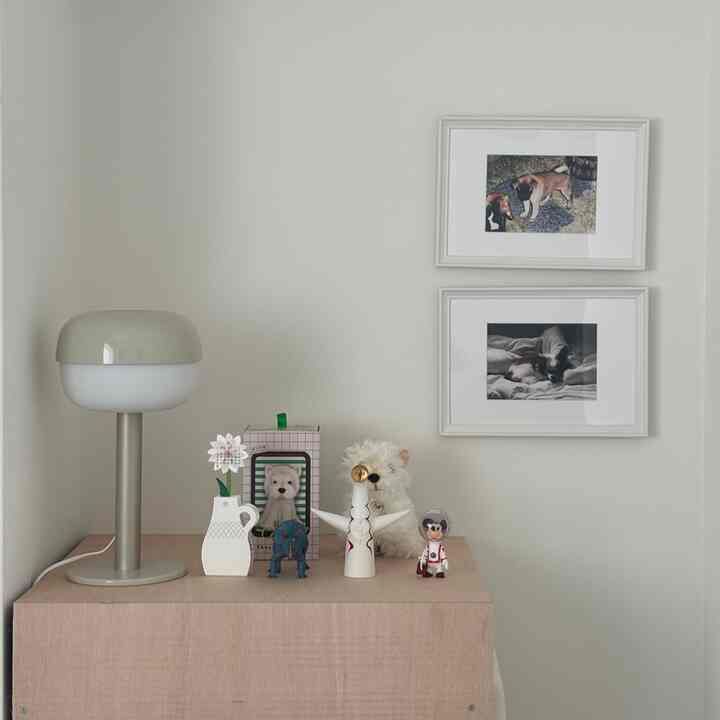 白とベージュの色調の寝室、テーブルランプと額縁が配置された落ち着いたミニマルなインテリア
