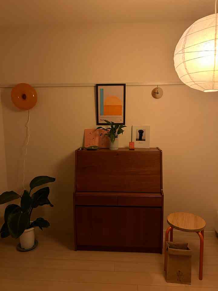 Warm brown and orange mid-century modern vintage room featuring a vintage bureau, potted plant, and lamps with a calm atmosphere