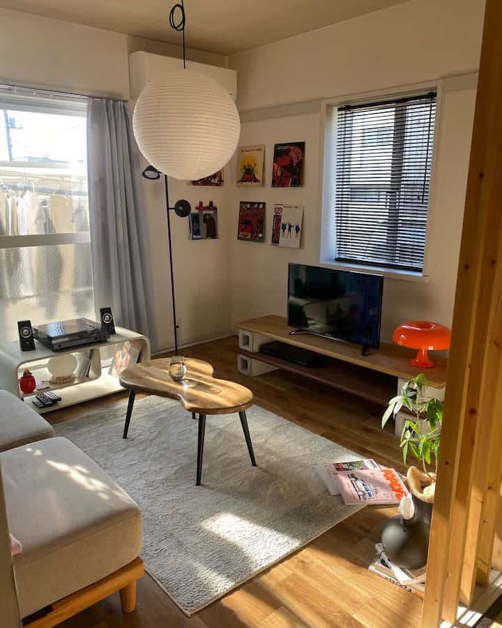 白と木目調の調和が美しいミッドセンチュリーモダンのリビング、ソファと木製のコーヒーテーブル、アナログレコードプレーヤーと額縁が置かれた温かみのある空間