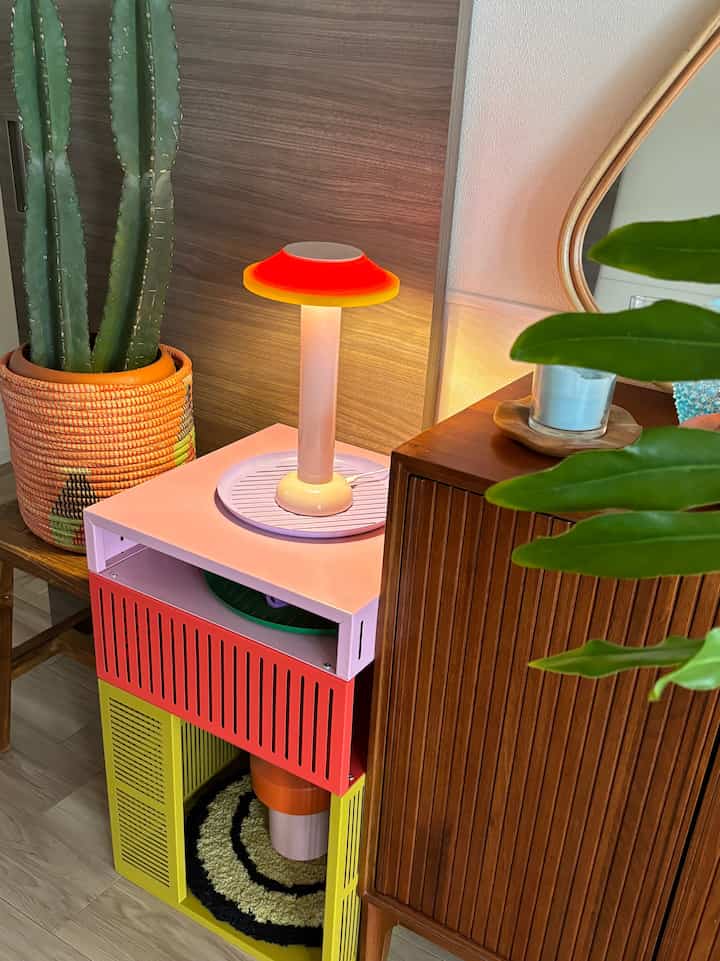 明るくカラフルなミッドセンチュリーモダンのリビング、鮮やかなTESAMMANS収納ユニットと植物が配置された雰囲気のある空間