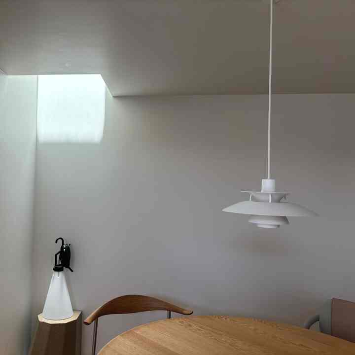 白と木目調が調和したダイニング、丸テーブルとペンダントライトが配置された印象的な空間