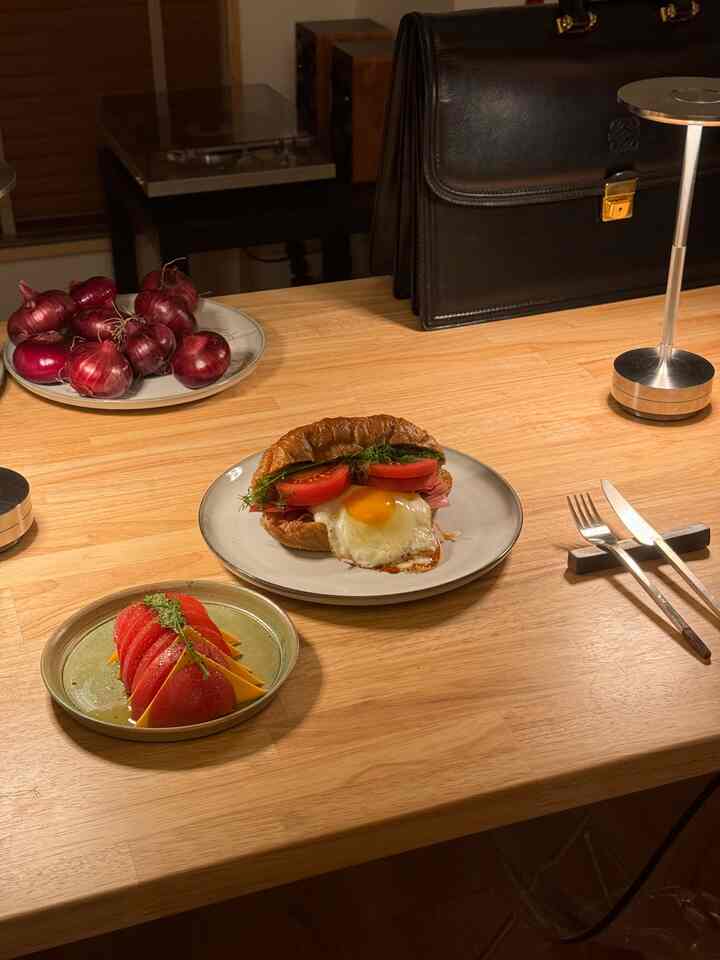 ナチュラルな木目調のダイニングテーブルが中心の一人暮らし用ダイニング、皿とカトラリーが落ち着いた雰囲気を作る空間