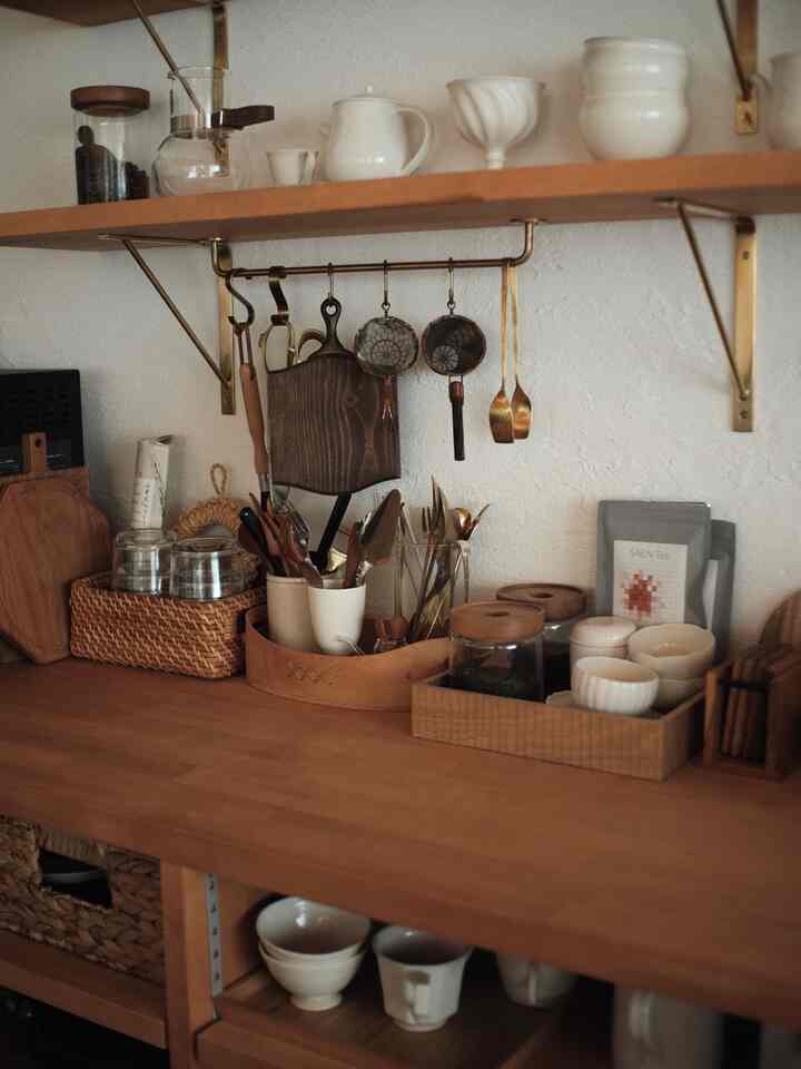 ナチュラルな木目調のキッチン棚とカウンターに、調理器具やグラスが整然と並ぶ雰囲気のあるキッチンスペース