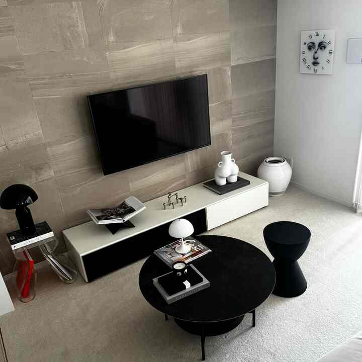 モノトーンのホワイトとブラックが調和するリビング、中央にコーヒーテーブルとスツールが配置されたモダンな空間