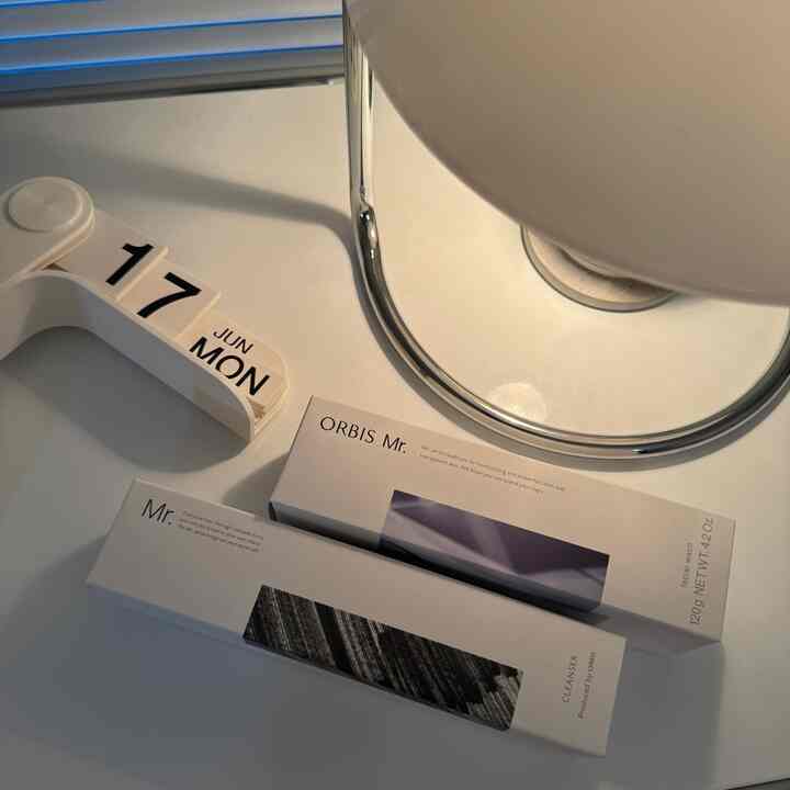 白いトーンのデスクにフリップカレンダーとORBIS Mr.の商品ボックスが配置されたシンプルなデスクスペース
