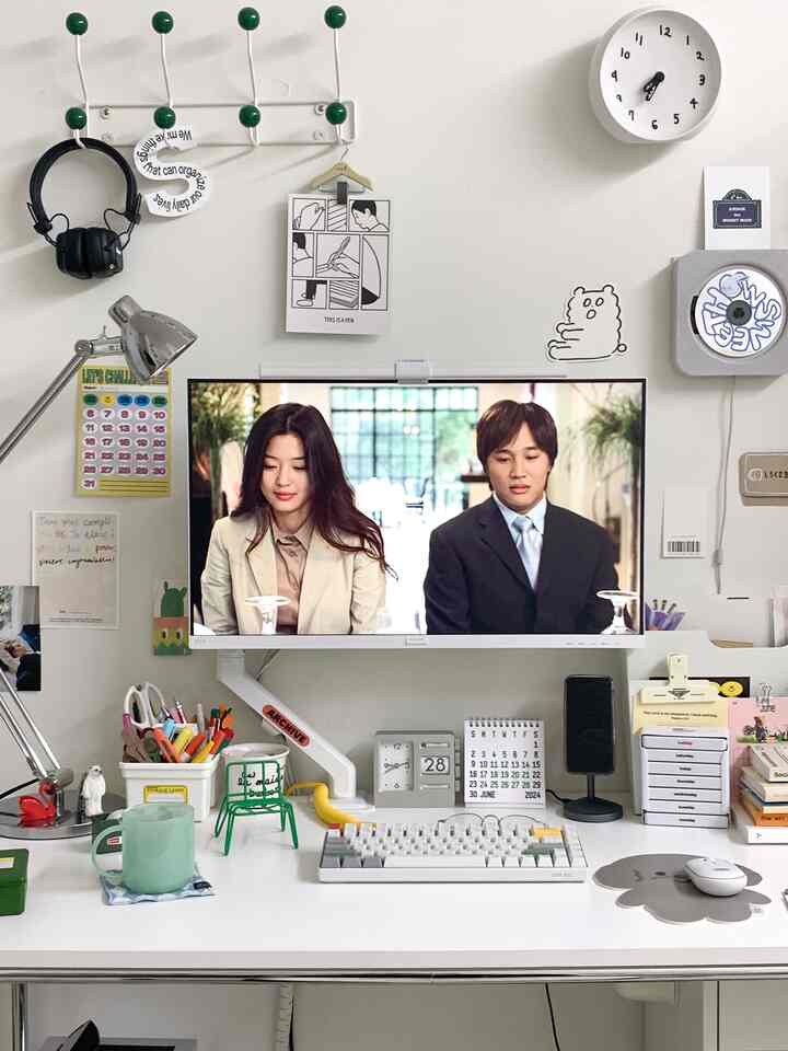 White-tone home office space featuring a monitor, desk, and neatly organized stationery in a simple modern setup