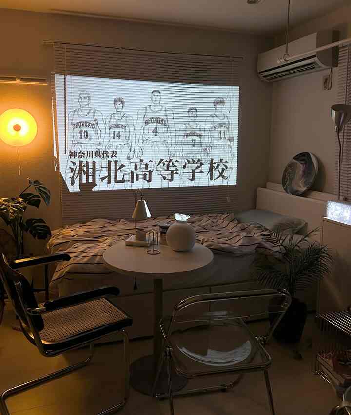 White and silver toned studio living room featuring Nebula Apollo projector displaying anime on blinds, creating a simple home cinema atmosphere