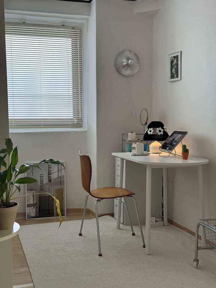 白と木目調のウォークインクローゼット兼書斎、テーブルランプとブラケットライトが配置されたシンプルモダンな作業スペース