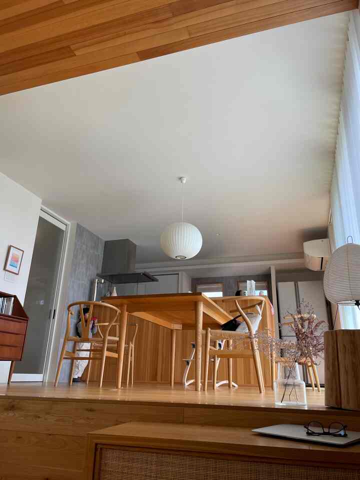 明るい木目調と白を基調としたダイニング、ダイニングテーブルと椅子、ペンダントライトが配置されたシンプルでジャパンディ風の印象的な空間