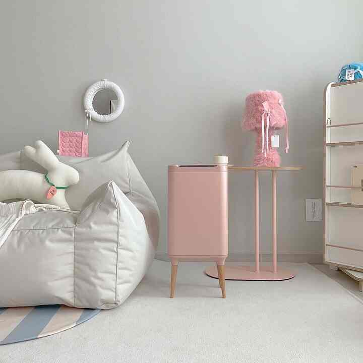 Soft beige and pink toned living room featuring a two-person bean bag sofa, pink side table, and furry lamp creating a cozy atmosphere