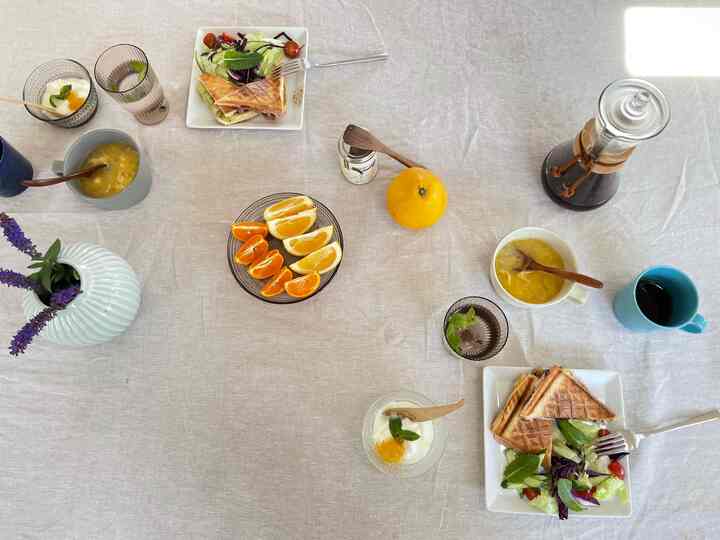 Beige tablecloth dining room featuring sandwiches, fruit plates, and Chemex coffee set in a stylish breakfast setting