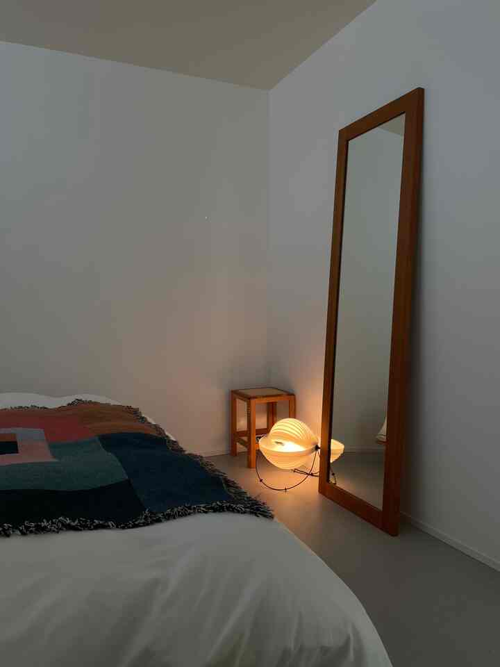 Modern bedroom with white walls and natural wood furniture, cozy lighting and colorful blanket accents