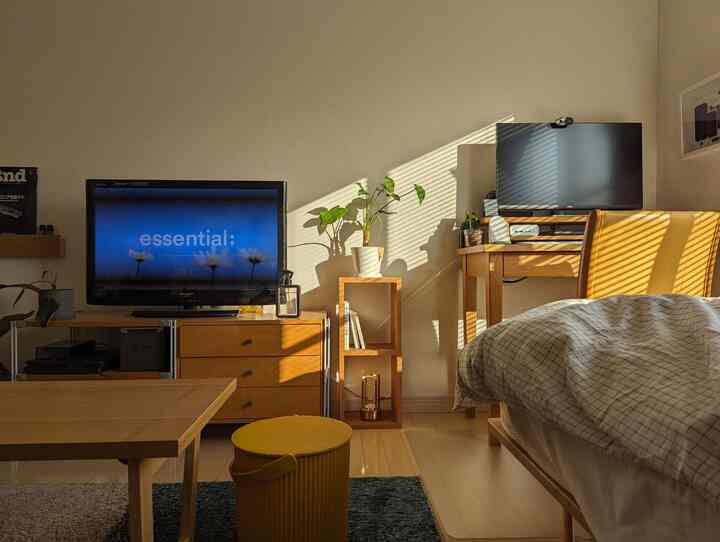Natural wood-toned single household bedroom with beige walls featuring sunlight blinds shadows creating a cozy atmosphere