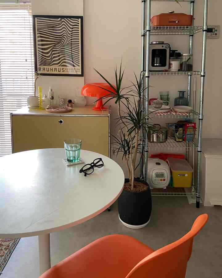 白とオレンジのトーンが特徴的なミッドセンチュリーモダンスタイルの一人暮らし1DKリビング、清潔で居心地の良い空間