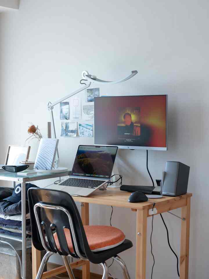 Natural toned compact home office featuring a wooden desk and black office chair in a cozy workspace