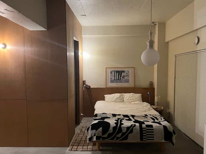 Wood-tone and white bedroom featuring a wooden bed frame and minimalist lighting, creating a cozy atmosphere