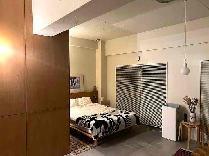 White and brown toned bedroom featuring wooden furniture and patterned blanket, presenting a modern natural atmosphere