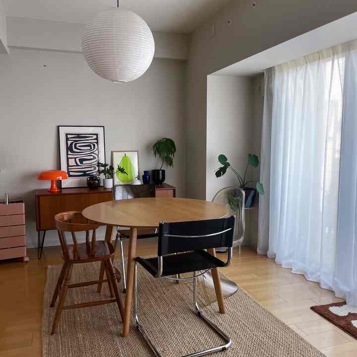 Natural toned dining room with white walls and curtains, featuring a round wood dining table and chairs
