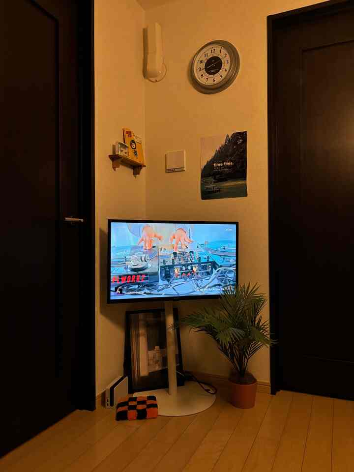 Natural wood-toned floor space featuring white TV stand and fake green plant in Korean interior style