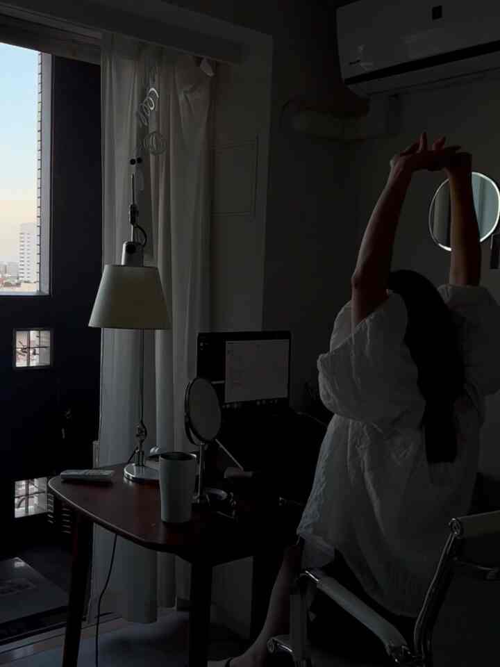 白とダークブラウンの色調のホームオフィス、デスクにはテーブルランプとノートパソコンが配置された雰囲気のある作業空間