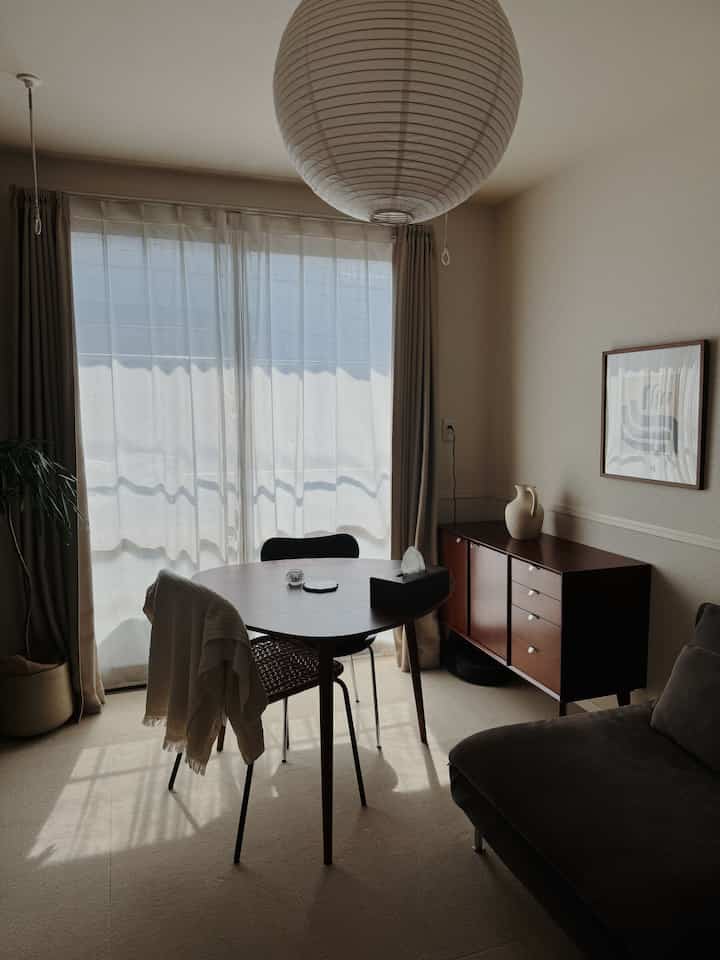 Natural-toned dining room featuring a round dining table and sideboard with a warm atmosphere