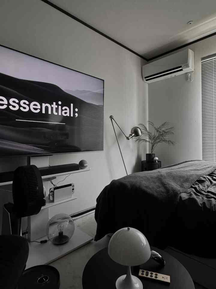 Monotone and white bedroom featuring bed, TV stand, and table lamp in a modern, clean space