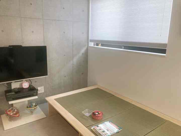 Natural tones and concrete wall in a living room featuring a tatami bed, creating a cozy atmosphere