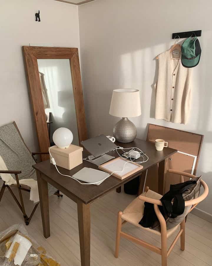 ナチュラルな木目調と白い壁のワンルームのホームオフィス、シンプルモダンな机と椅子が配置された落ち着いた空間
