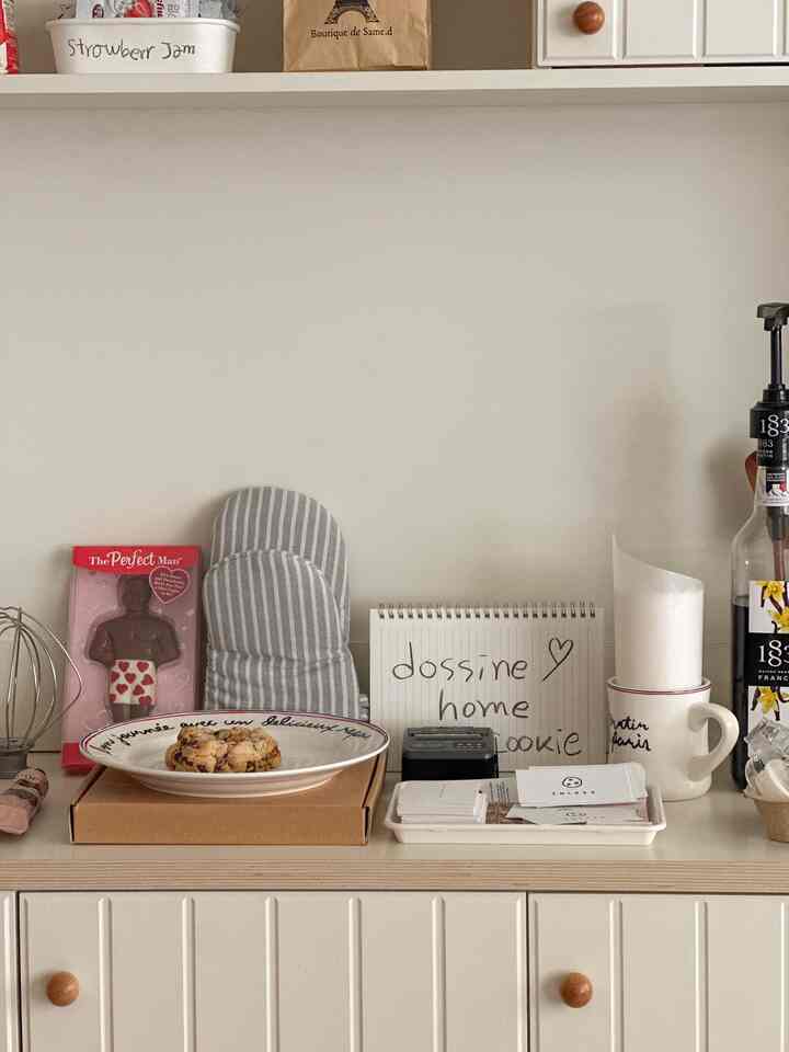 白とベージュの色調のキッチン空間、クッキーが乗った皿とマグカップ、トレイが整えられた雰囲気のあるインテリア