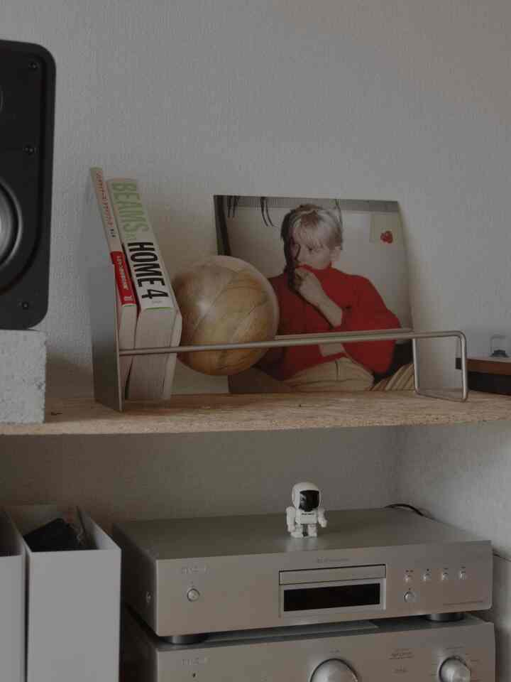 Modern bookshelf shelf featuring natural wood tones and silver electronic equipment with a clean atmosphere