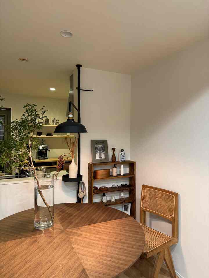 明るい白い壁とブラウンの木目調の丸いダイニングテーブルと椅子が配置されたナチュラルなダイニングルームの雰囲気のあるインテリア