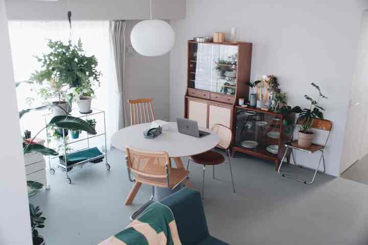 ホワイトとブラウンの色調が調和したダイニングルーム、丸テーブルと椅子、緑の植物が配置されたナチュラルモダンなインテリア