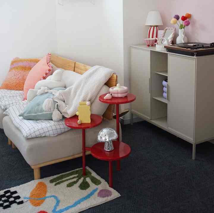 ピンクと赤の色調のリビング、ベージュのソファと赤いサイドテーブルが配置された雰囲気のあるインテリア