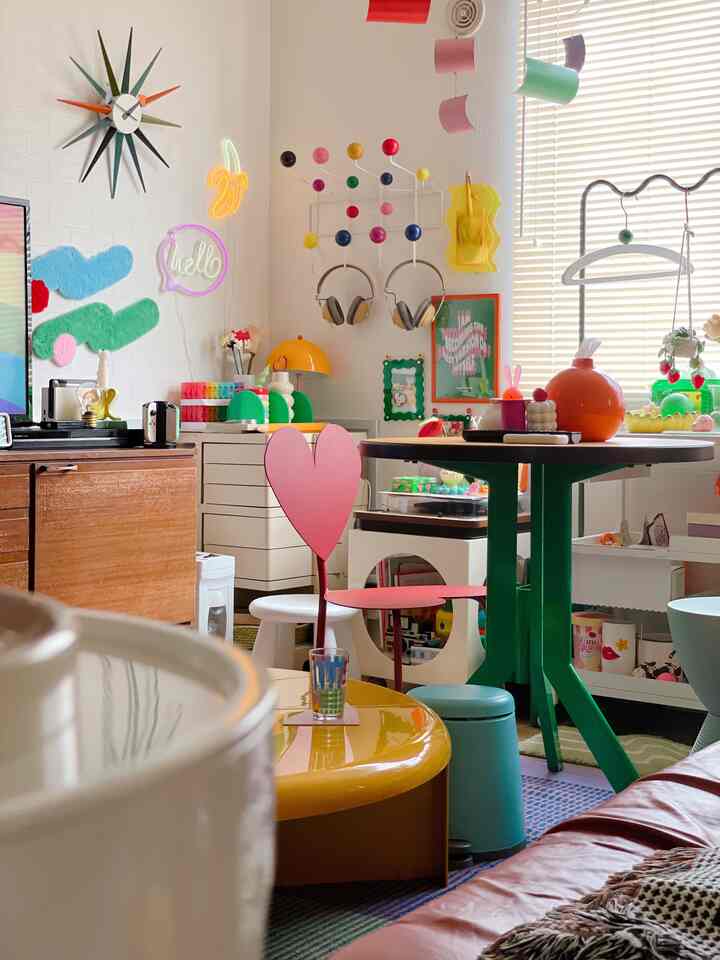 白を基調に多彩な色彩が映えるリビング、ハート型の椅子とレトロなインテリアが印象的な空間