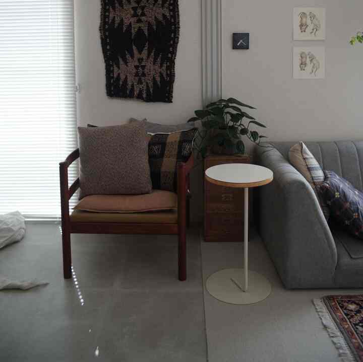 Natural wood-tone furniture and gray sofa in a vintage-style living room with bright blinds filtering light