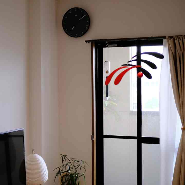 Beige and brown toned living room with wall clock, curtains by sliding glass door, and floor lamp creating a calm atmosphere