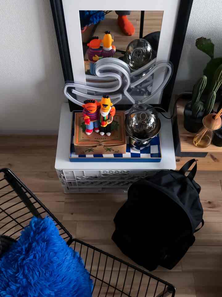Wood tone floor and white flip box in a small room, featuring a black backpack and a blue cushion creating a cozy atmosphere