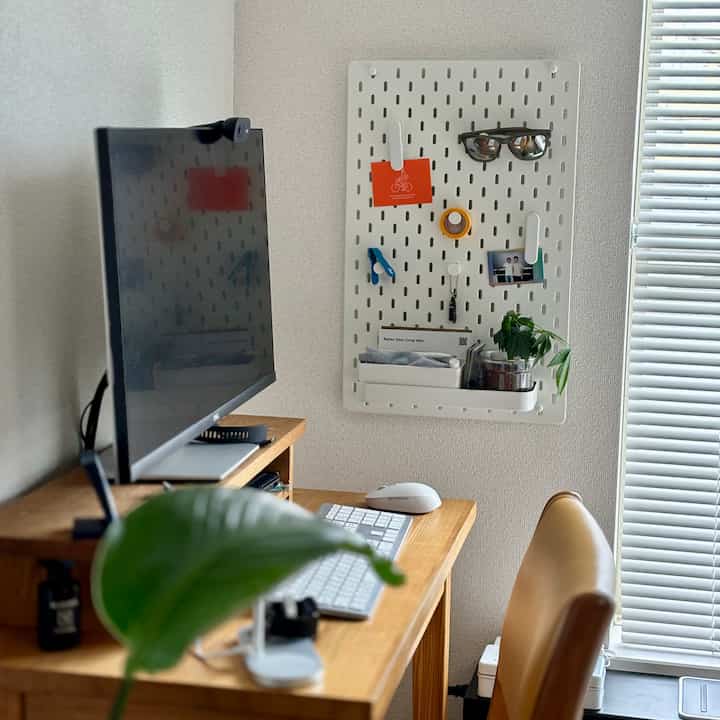 ナチュラルな木目調と白を基調とした一人暮らしのホームオフィス、壁に取り付けられたイケアのスコーディスペグボードが収納と装飾を兼ね備える空間