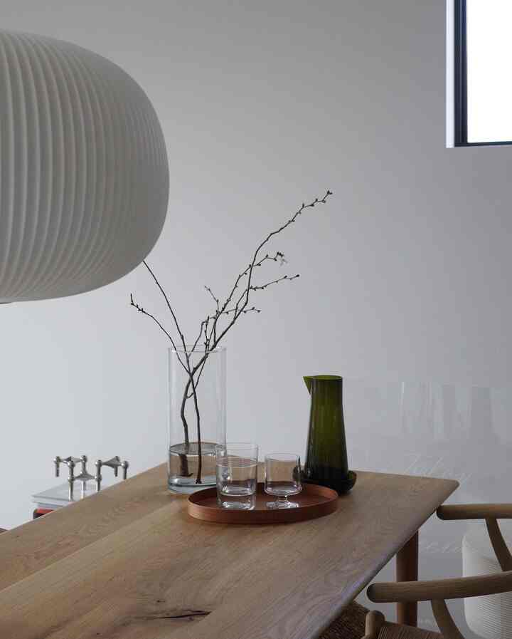 白い壁と木目調のダイニングルーム、透明なガラス容器とカラフェが置かれた清潔感のあるインテリア