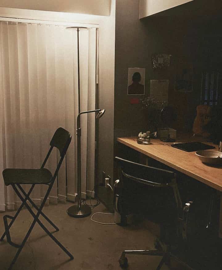 ブラウンとホワイトのトーンの小さなホームオフィス、バースツールとフロアランプが配置された落ち着いた作業空間