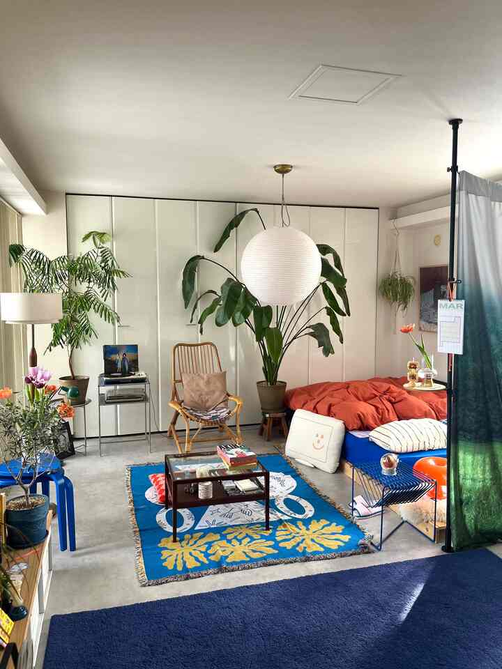 Bright natural toned bedroom featuring an orange duvet and multiple plants, creating a cozy atmosphere