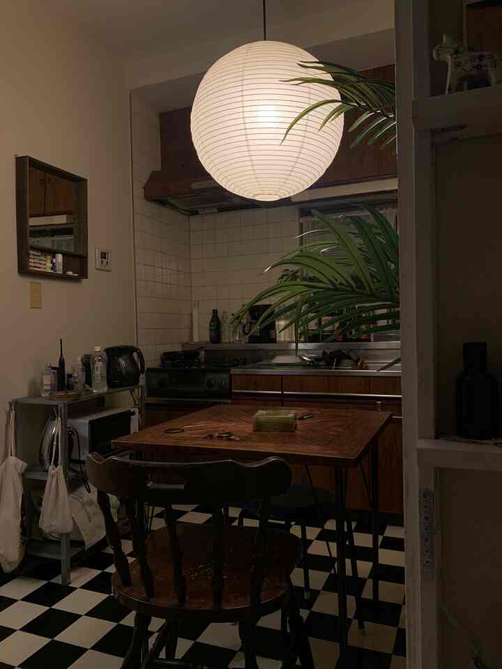 温かみのある木目調とモノトーンのタイル床が特徴的なアパートのキッチン、ペンダントライトが落ち着いた雰囲気を演出するインテリア。