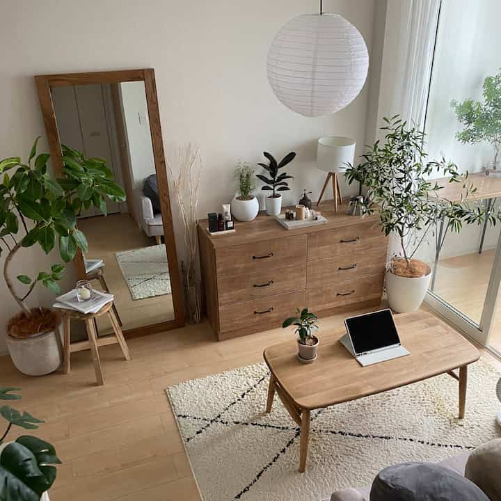 木目調と白を基調としたリビング、全身鏡と多様な観葉植物が配置された、清潔感と自然の雰囲気あるインテリア