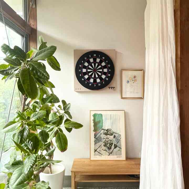 Beige toned entrance space with wood tone bench, featuring a darts board and framed art on the wall creating a natural cozy atmosphere