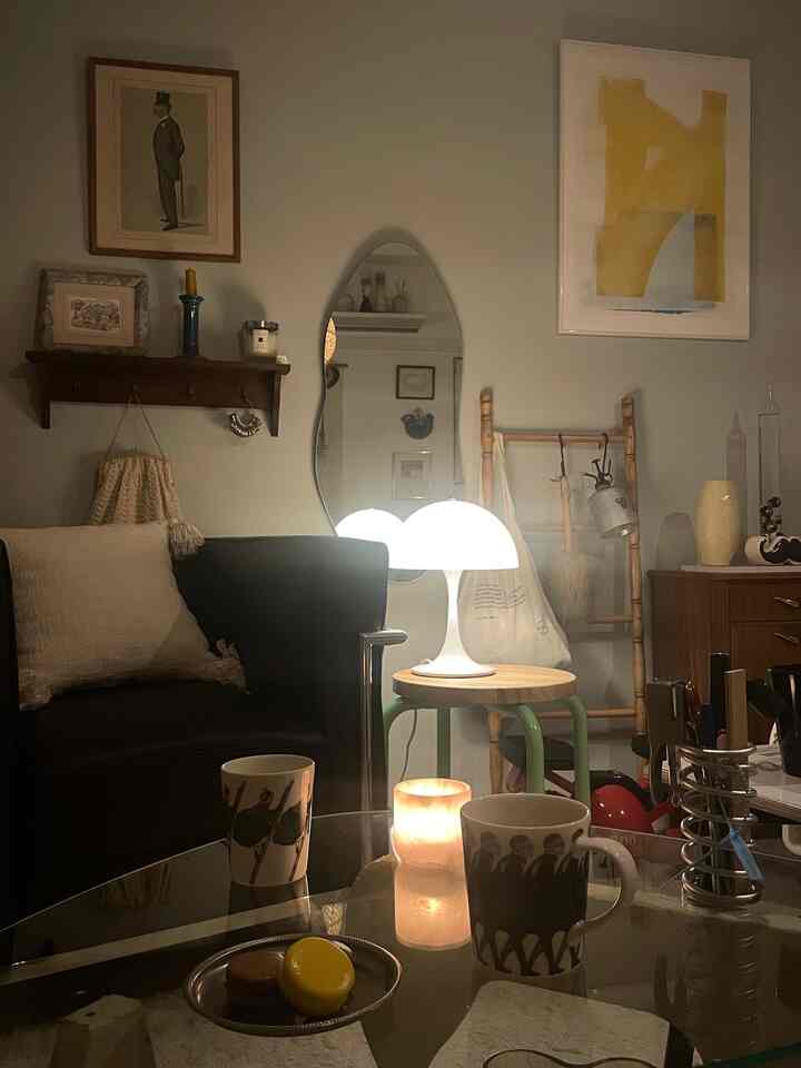 暖かみのある木目調とレトロスタイルの一人暮らしのリビング、アームチェアやスツールと柔らかな照明が配置された雰囲気のあるインテリア