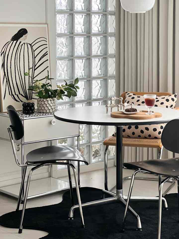 Modern dining room in white and black tones featuring a round table and assorted chairs in a clean arrangement