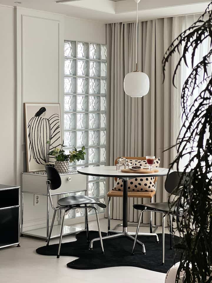 ホワイトとブラックのトーンのリビングルームおうちカフェ、円形テーブルとアームチェア、ブラックラグが調和した印象的なミッドセンチュリーモダンインテリア